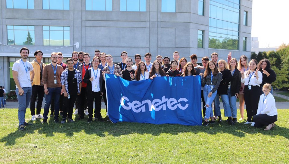 Pasantes sosteniendo la bandera de Genetec fuera de nuestra oficina de Montreal
